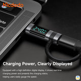 Laptop with a charging cable displaying real-time charging power on a dark surface, featuring the Mcdodo brand.